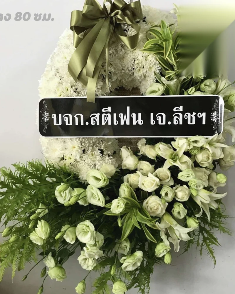 พวงหรีดดอกไม้สดสีขาวผูกโบว์ตั้งพิงขาตั้งไม้