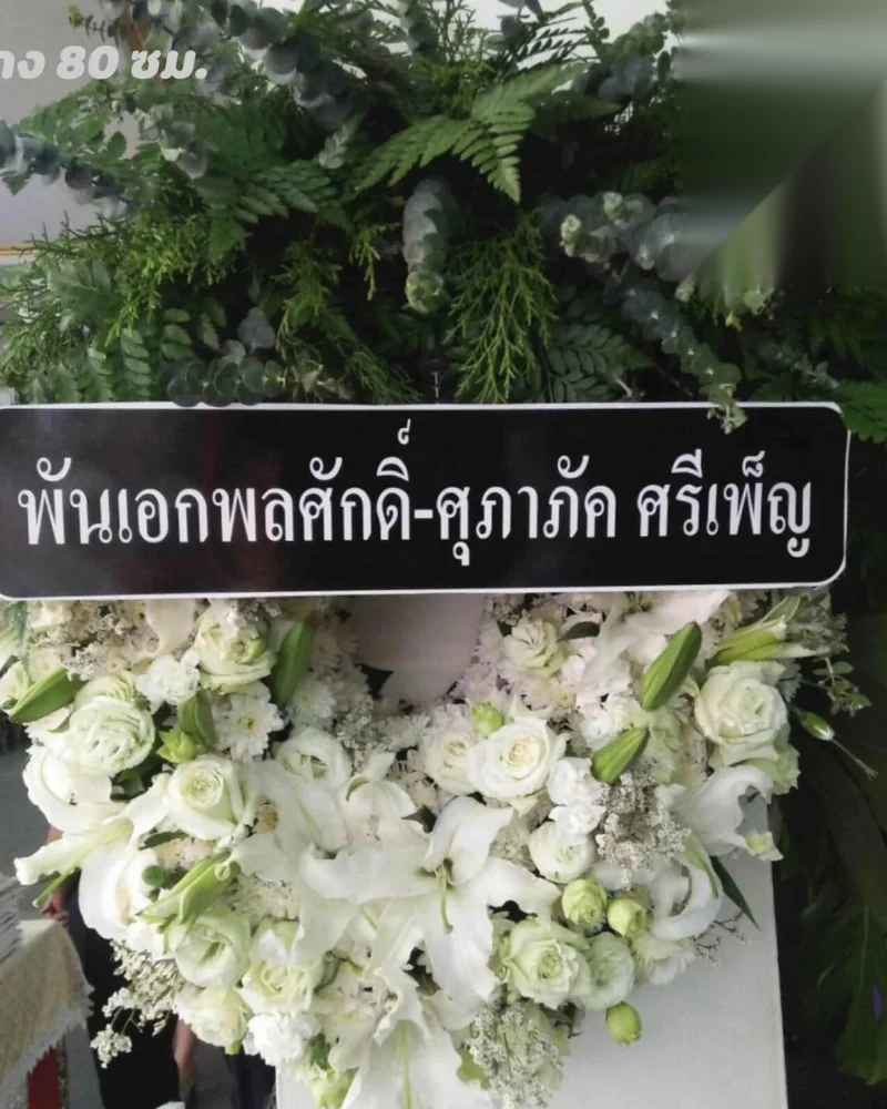 พวงหรีดดอกไม้สดสีขาวแซมใบเขียวตั้งหน้าศาลา