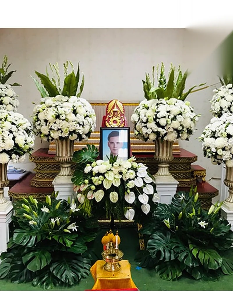 ดอกไม้หน้าศพและรูปผู้ล่วงลับตั้งอยู่หน้าศาลาวัดในงานสวดพระอภิธรรม