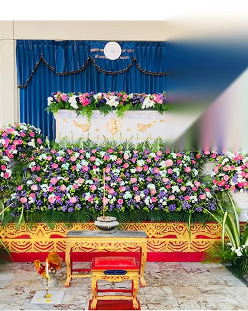 ศาลาวัดที่ตั้งหีบศพและจัดดอกไม้หลากสีไว้ด้านหน้าตลอดแนว