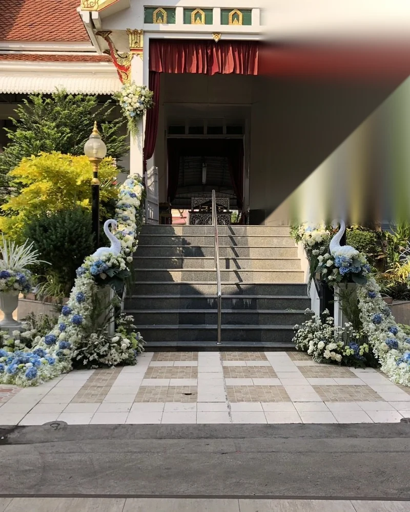 ทางขึ้นเมรุที่ประดับดอกไม้ไว้สองข้างทางเดินในวันฌาปนกิจ