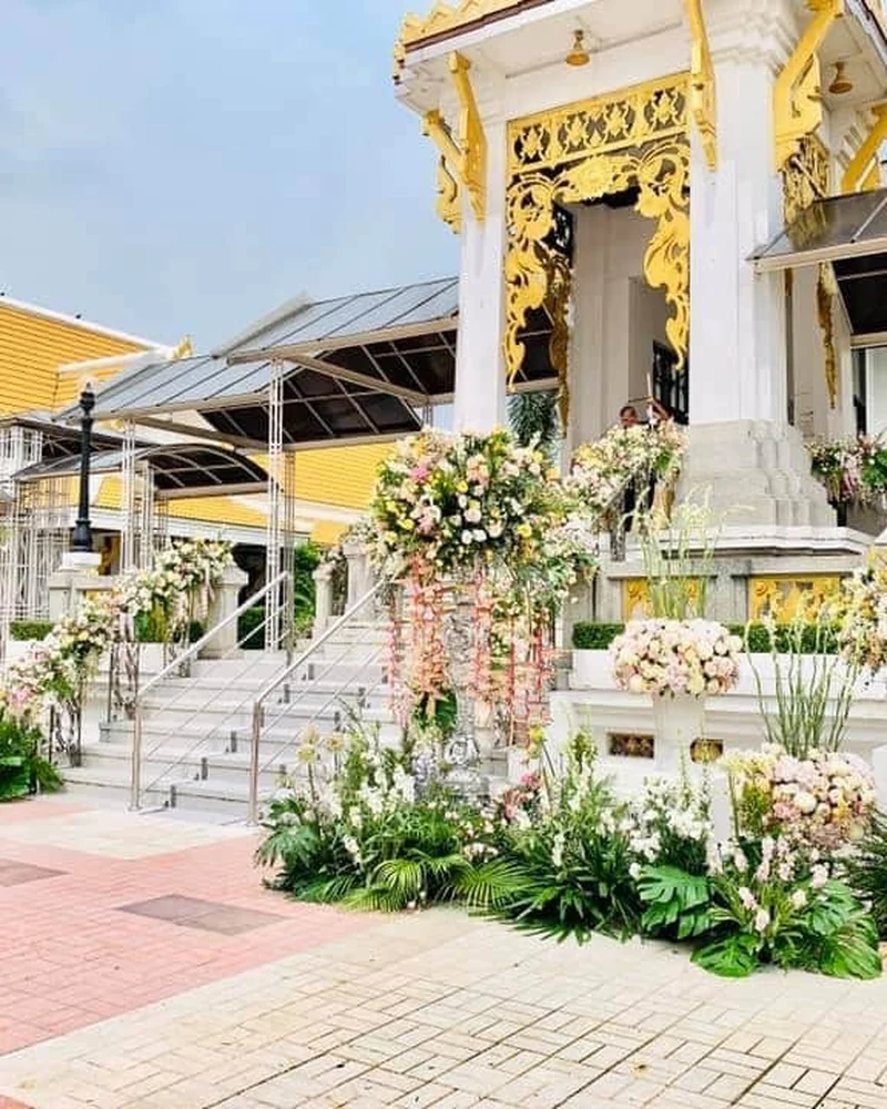 แจกันดอกไม้ไว้อาลัยโทนขาวตั้งเรียงหน้าอาคารประกอบพิธีของวัด